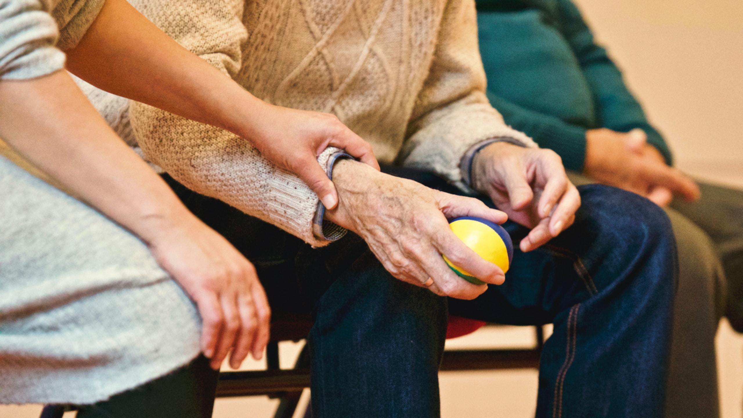 A family member holding a man's hand in the doctor's waiting room office.