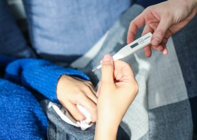 a woman holding a thermometer as she measures her fever